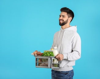 Man holding basket with fresh products on color background, space for text. Food delivery service