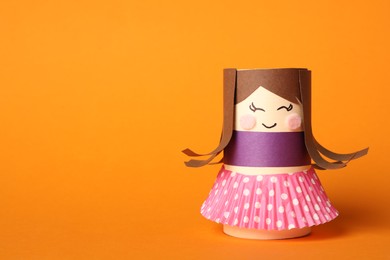 Toy doll made of toilet paper hub on orange background. Space for text
