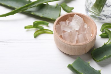 Photo of Aloe vera gel and slices of plant on white wooden table, closeup. Space for text
