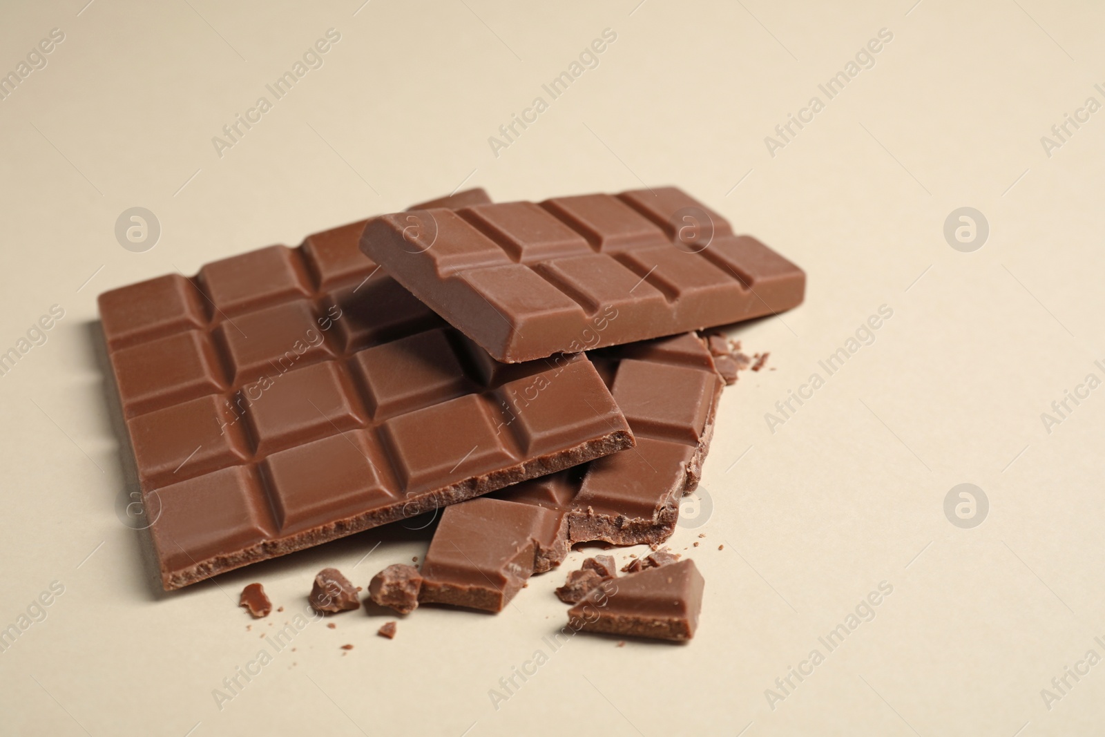 Photo of Delicious milk chocolate bars on beige background