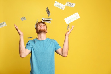 Photo of Portrait of happy lottery winner under money rain on yellow background