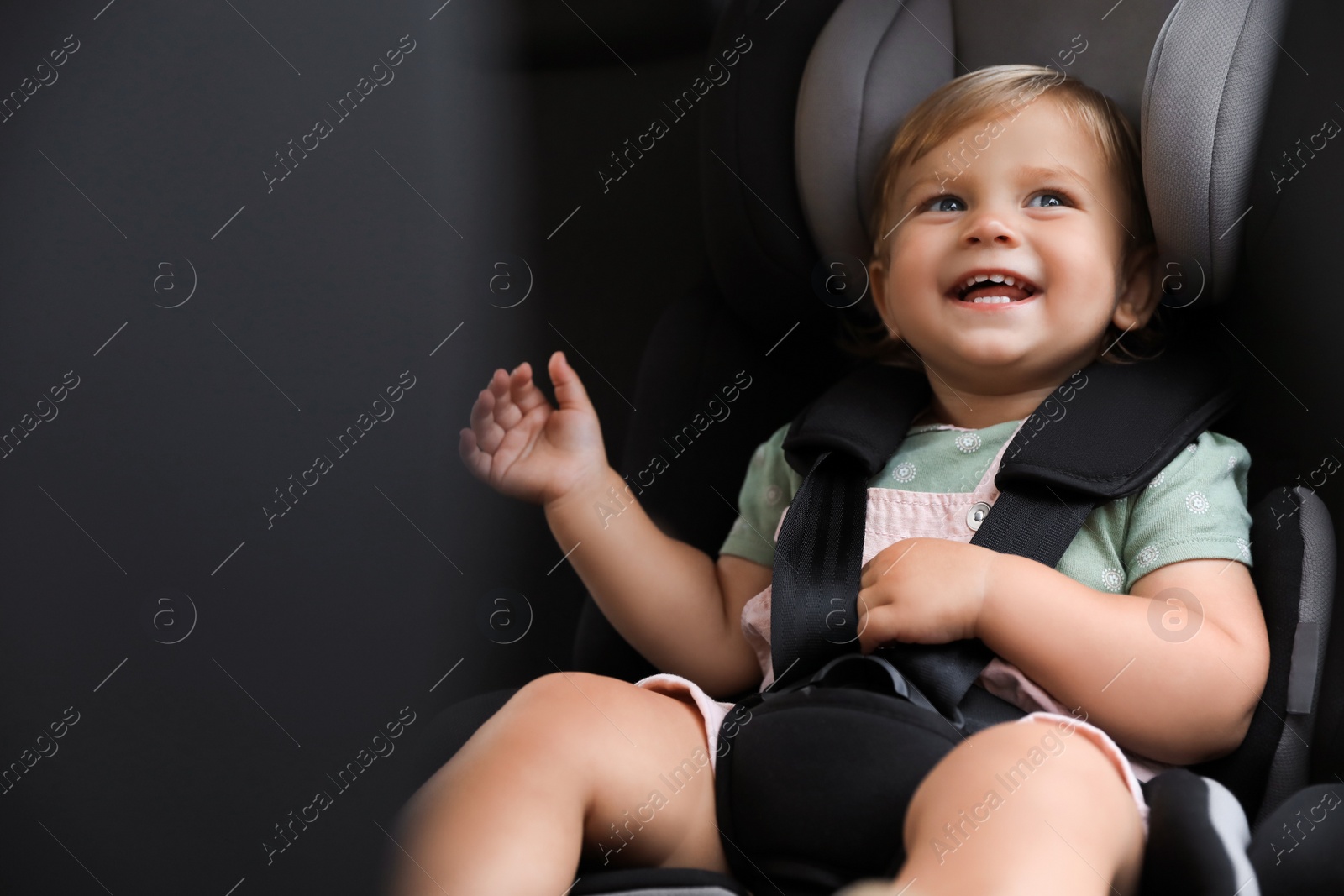 Photo of Cute little girl sitting in child safety seat inside car