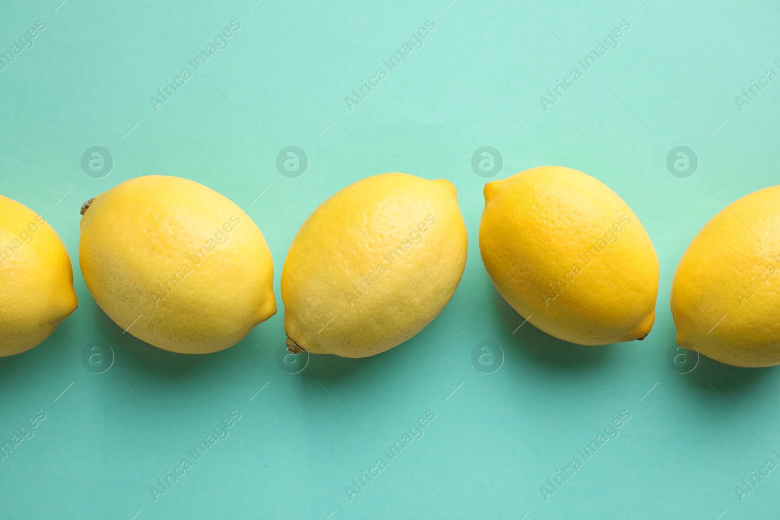 Photo of Fresh lemons on turquoise background, flat lay
