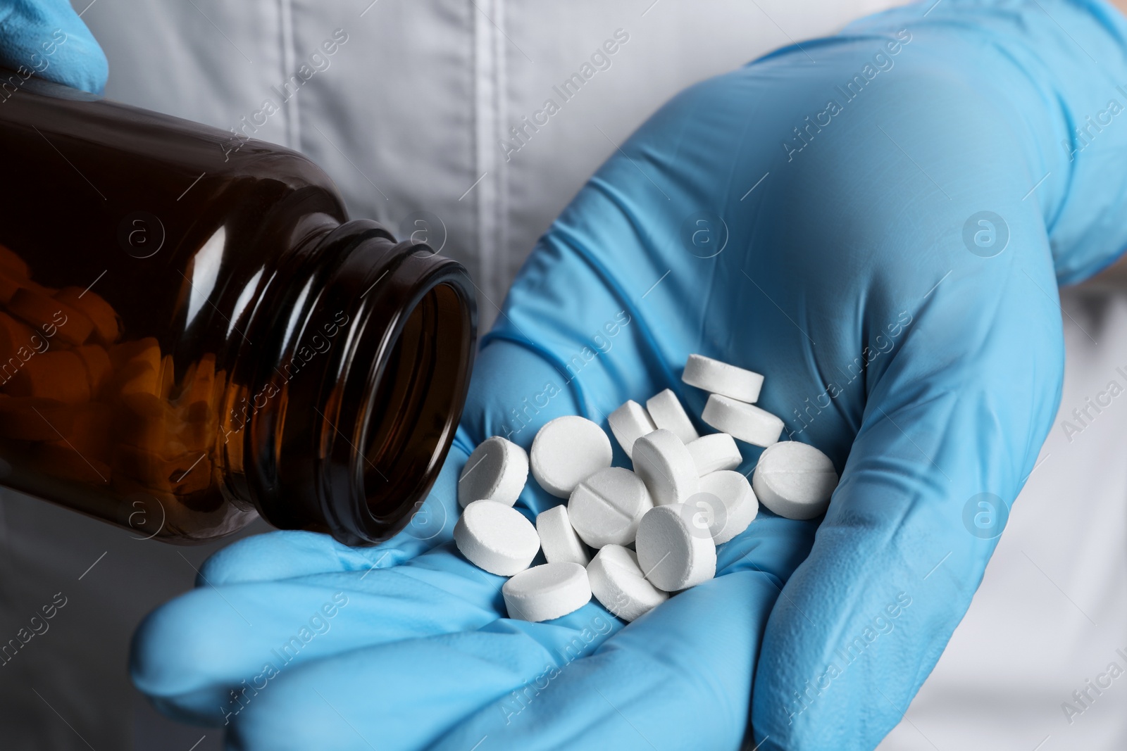 Photo of Doctor pouring pills from bottle onto hand, closeup view