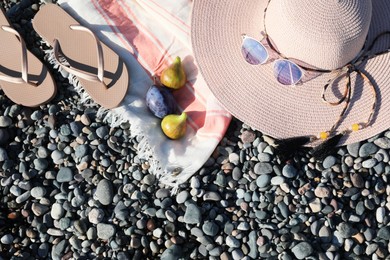 Photo of Beautiful hat with sunglasses and flip flops on pebbles, flat lay. Space for text