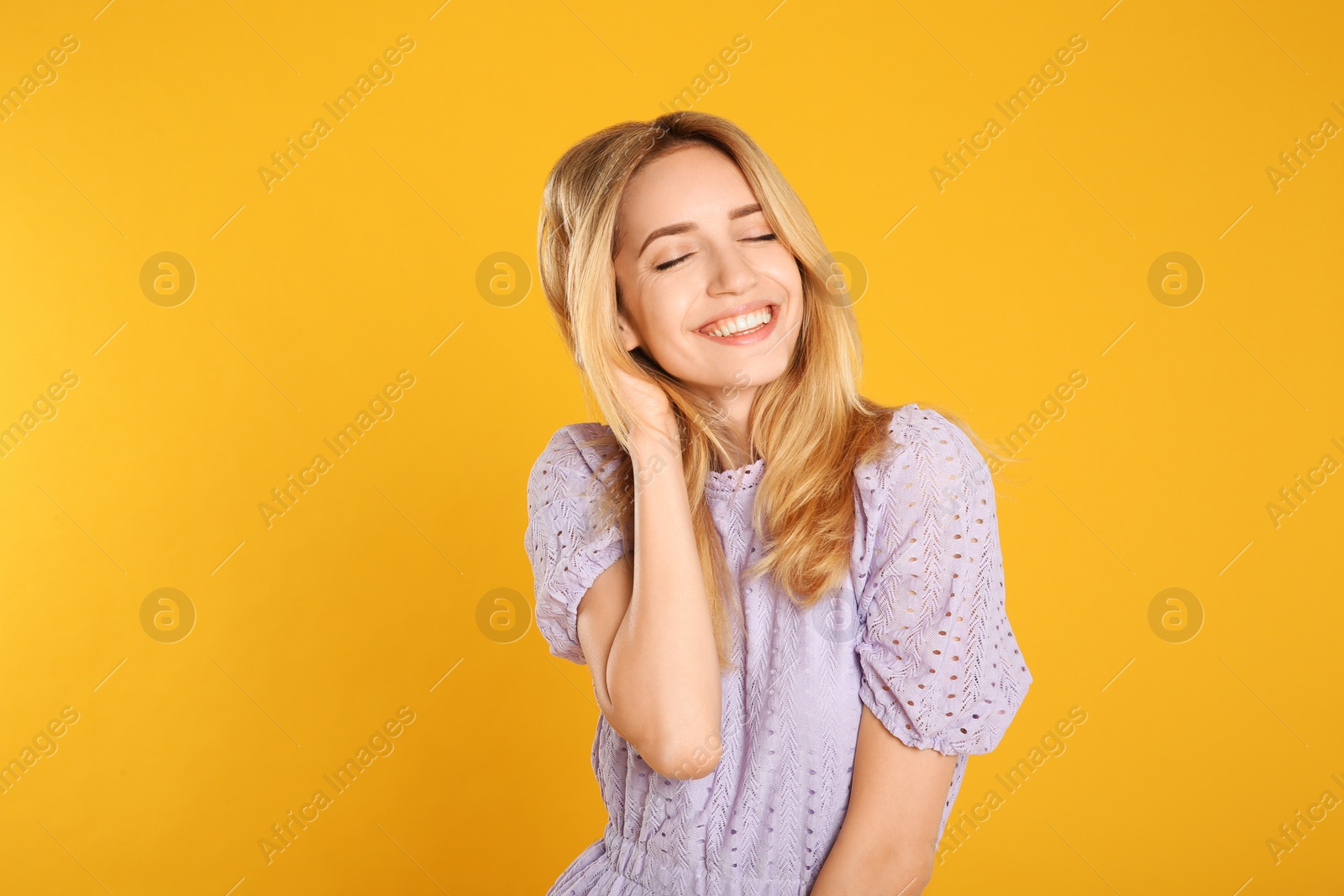 Photo of Portrait of beautiful young woman with blonde hair on yellow background