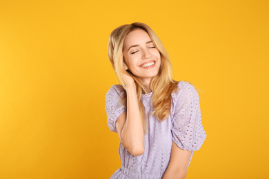 Photo of Portrait of beautiful young woman with blonde hair on yellow background