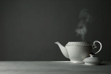 Photo of Ceramic teapot on table against grey background. Space for text