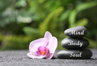 Stones with words Mind, Body, Soul and orchid on sand. Zen lifestyle