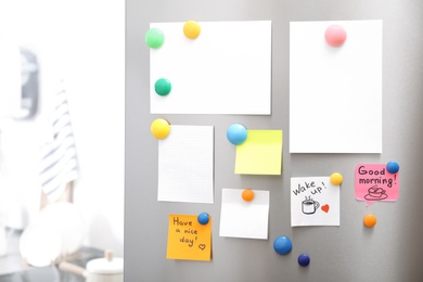 Photo of Many notes and empty sheets with magnets on refrigerator door in kitchen. Space for text