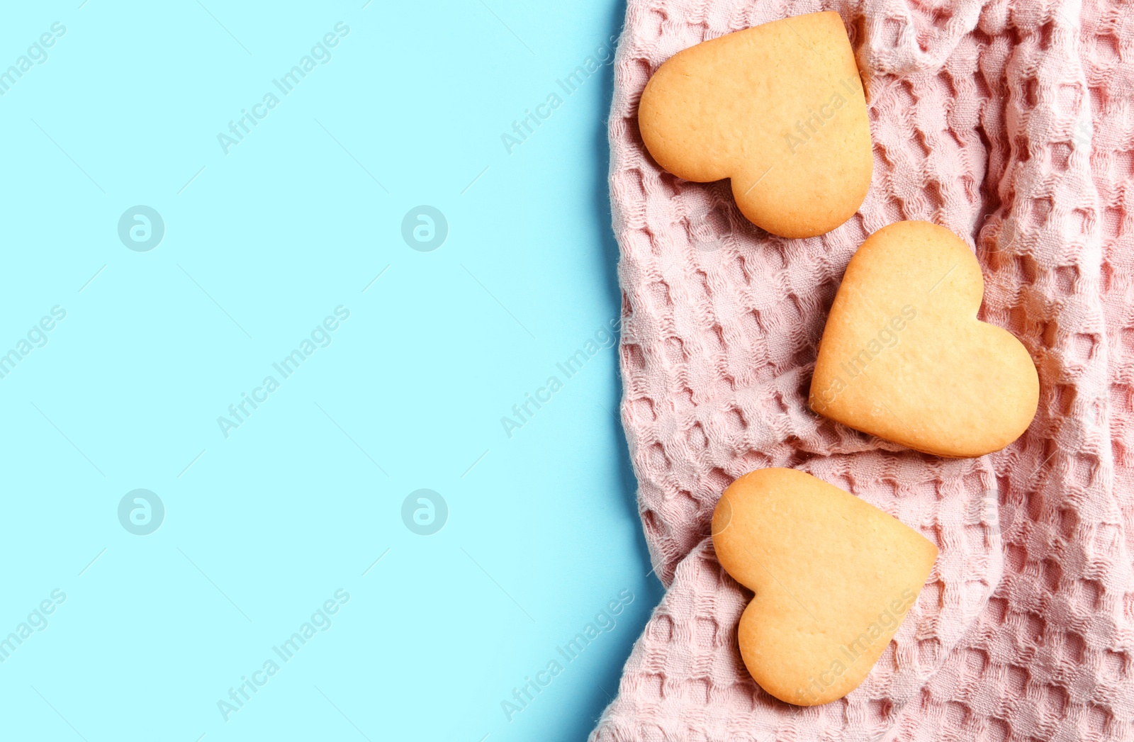 Photo of Homemade heart shaped cookies with napkin and space for text on color background, top view