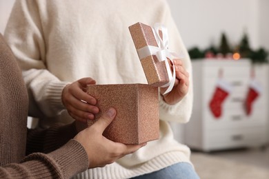 Photo of Woman opening Christmas gift from her boyfriend at home, closeup