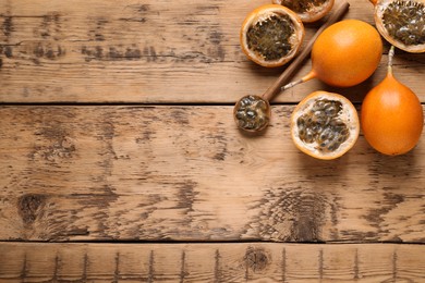 Photo of Delicious ripe granadillas on wooden table, flat lay. Space for text