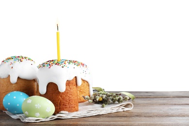 Photo of Easter cakes and painted eggs on wooden table against white background. Space for text