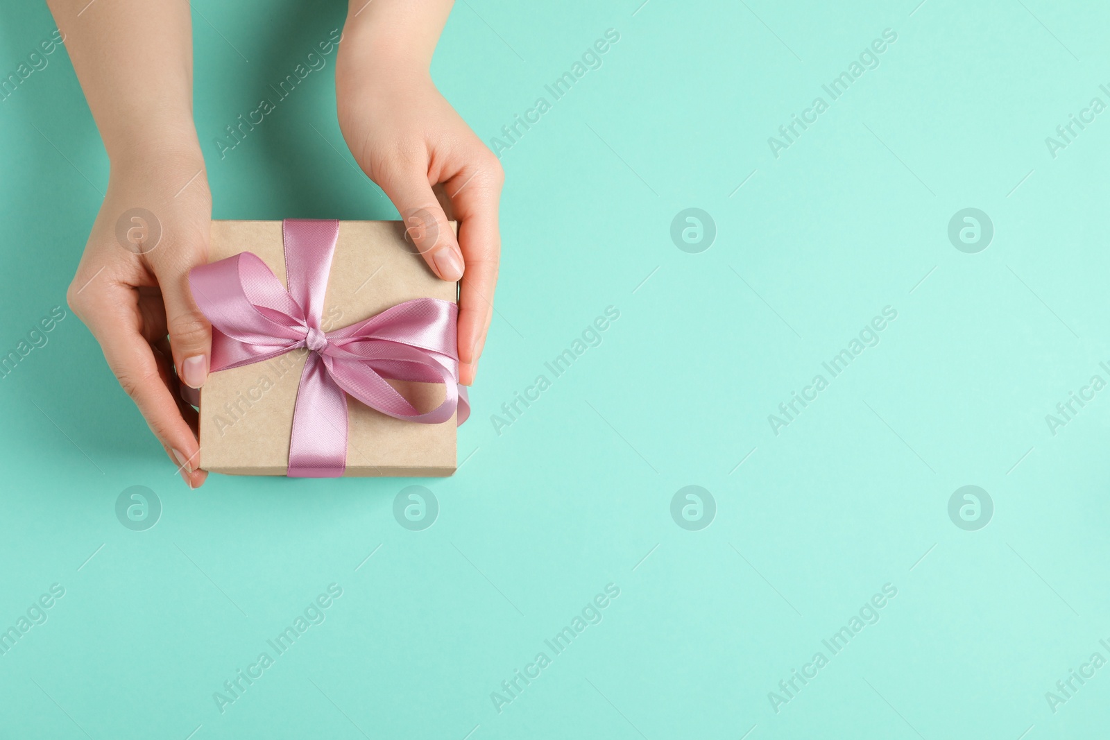 Photo of Woman with gift box on turquoise background, top view. Space for text
