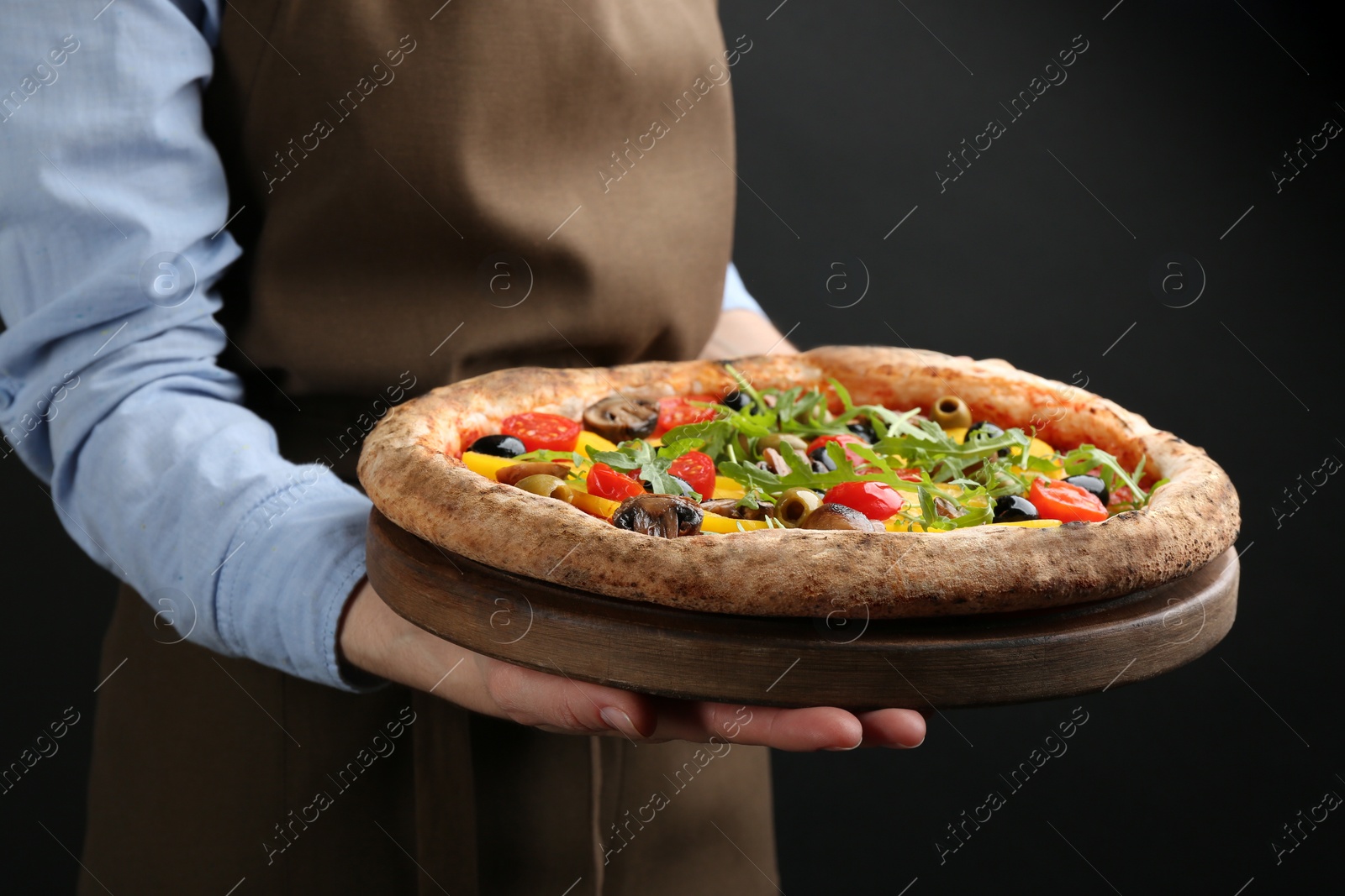 Photo of Woman holding tasty vegetable pizza on black background, closeup