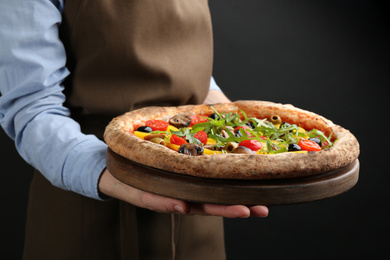 Photo of Woman holding tasty vegetable pizza on black background, closeup