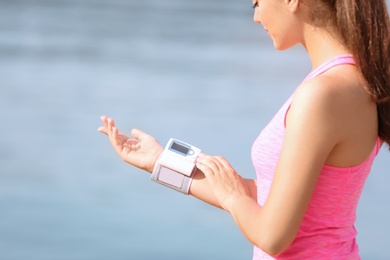 Young woman checking pulse outdoors on sunny day