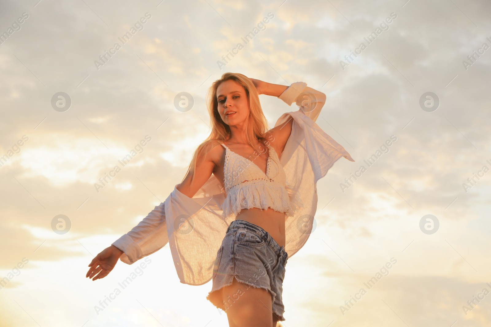 Photo of Young woman with beautiful blond hair outdoors at sunset