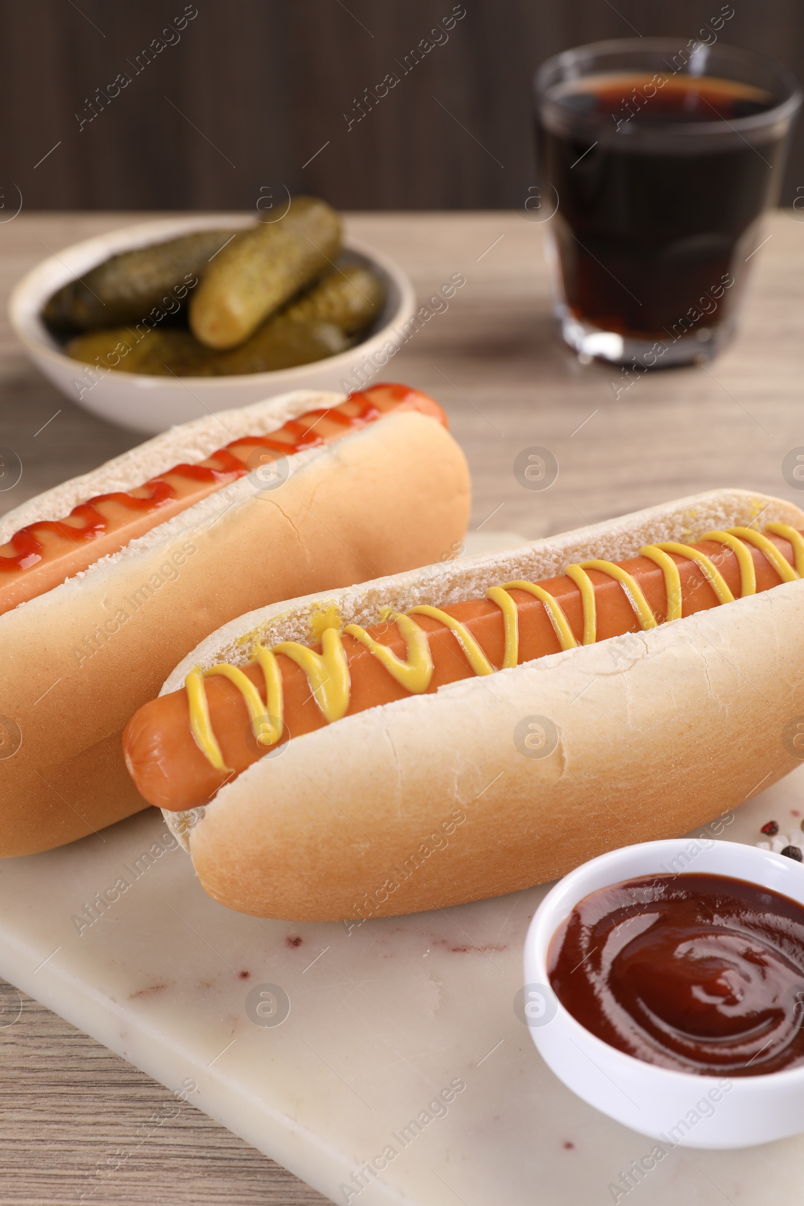 Photo of Tasty hot dogs with mustard and ketchup on wooden table