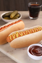 Photo of Tasty hot dogs with mustard and ketchup on wooden table