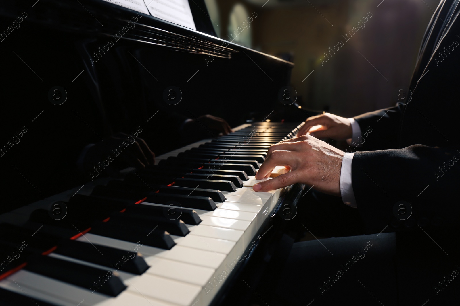 Photo of Man playing piano indoors, closeup. Talented musician