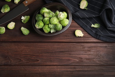 Fresh Brussels sprouts on brown wooden table, flat lay. Space for text