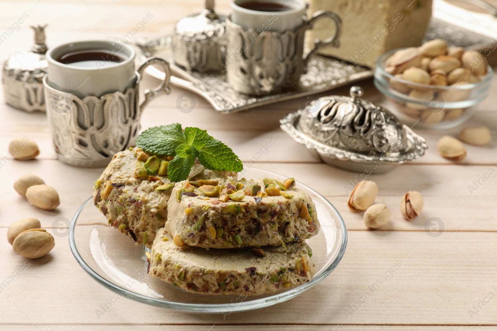 Photo of Tasty halva with pistachios and mint served on wooden table