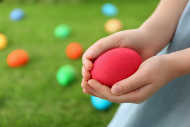 Photo of Little girl with painted Easter egg outdoors, closeup