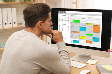 Photo of Handsome man using calendar app on computer in office