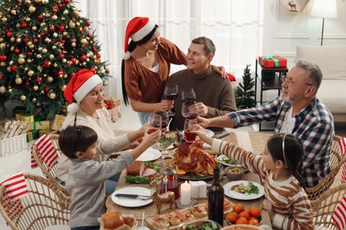 Happy family clinking glasses of drinks at festive dinner indoors. Christmas celebration
