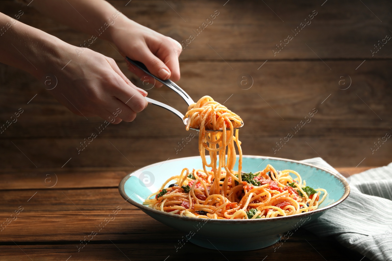 Photo of Woman eating delicious pasta at wooden table, closeup