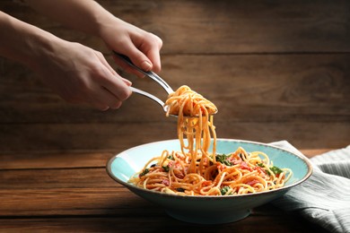 Photo of Woman eating delicious pasta at wooden table, closeup