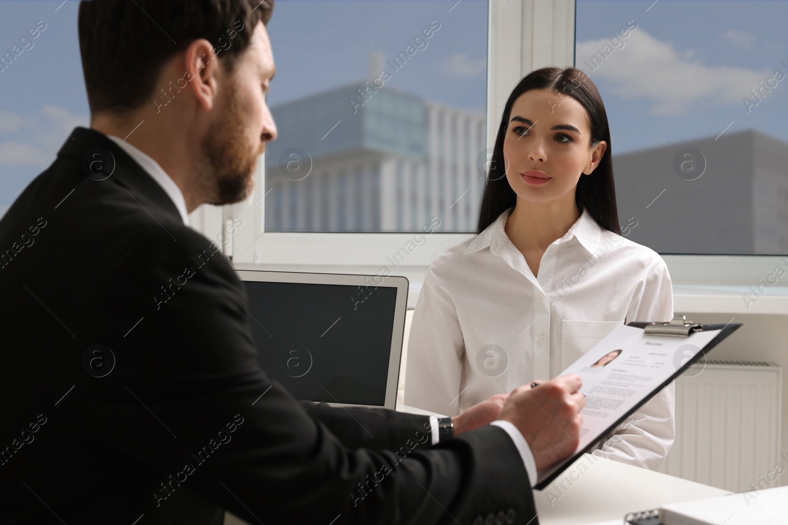 Photo of Human resources manager reading applicant's resume during job interview in office