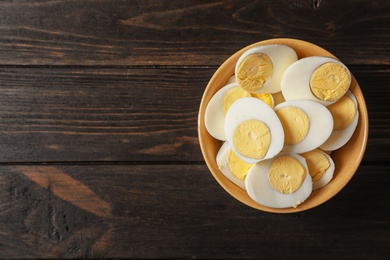 Photo of Bowl with boiled eggs on wooden background, top view. Space for text