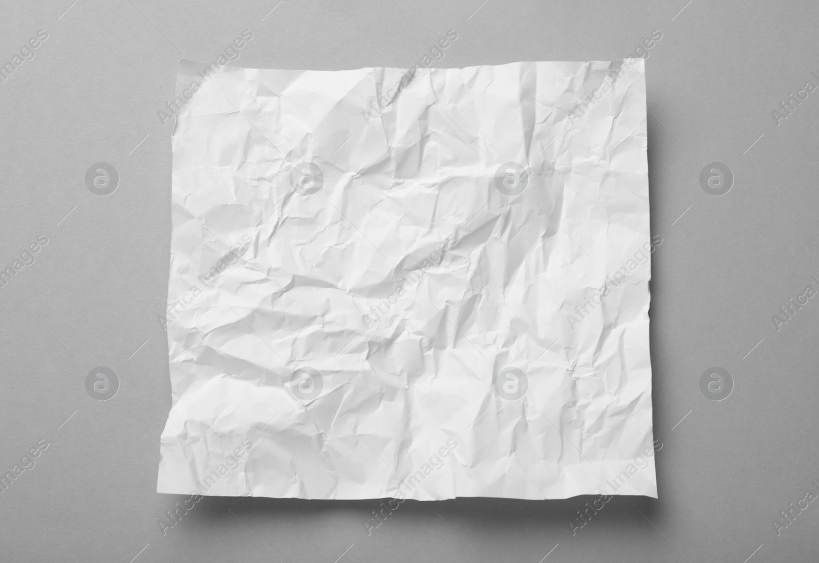 Photo of Sheet of white crumpled paper on grey background, top view