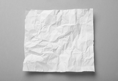 Photo of Sheet of white crumpled paper on grey background, top view