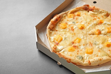 Photo of Carton box with cheese pizza on grey background, space for text. Food delivery service