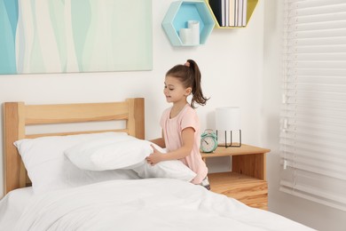 Cute girl changing bed linens in children room