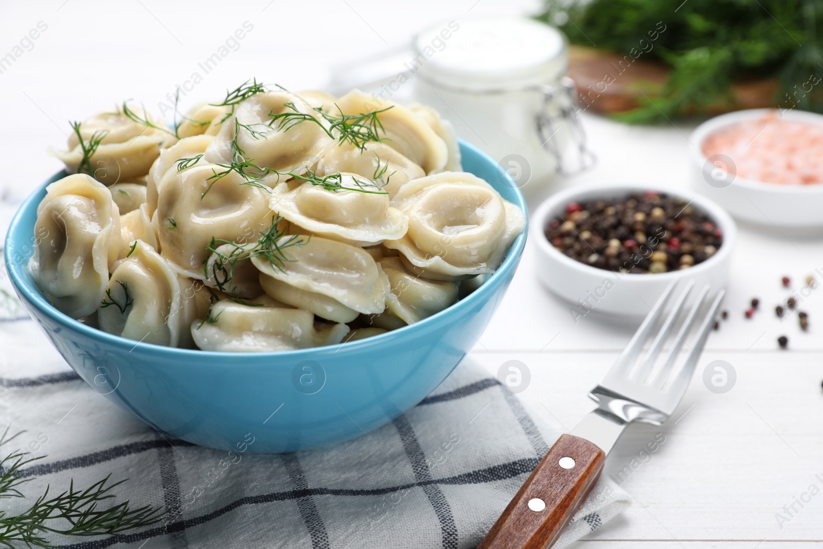 Photo of Delicious dumplings with dill on white wooden table, closeup