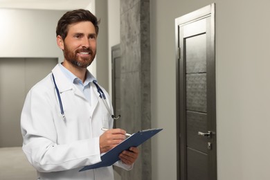 Photo of Doctor in white coat with stethoscope and clipboard indoors. Space for text