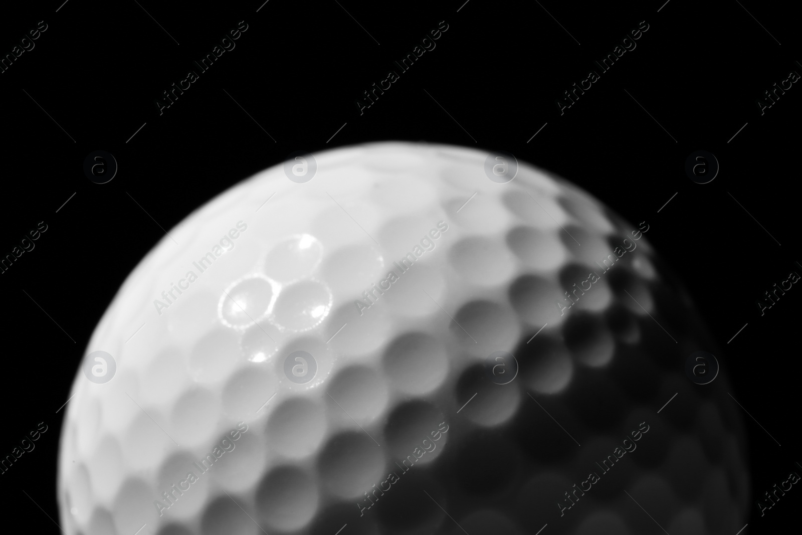 Photo of New golf ball against dark background, closeup