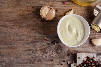 Photo of Flat lay composition with garlic sauce on wooden background. Space for text