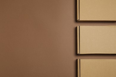 Photo of Many closed cardboard boxes on brown background, flat lay. Space for text