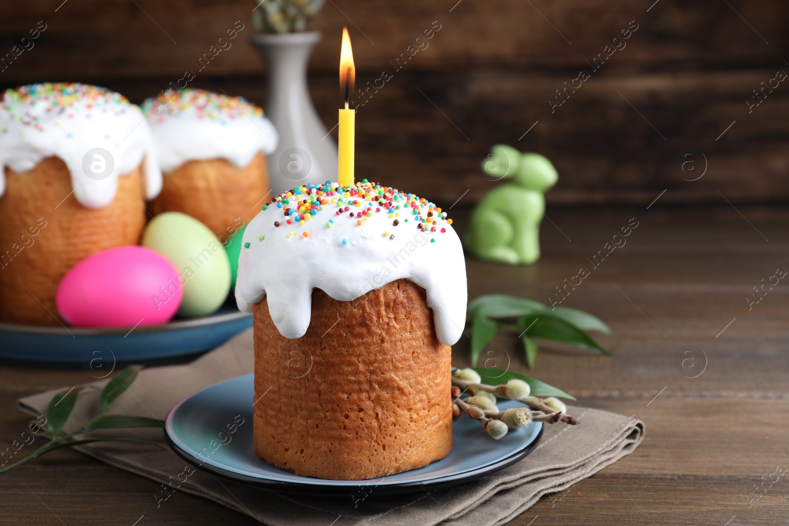 Photo of Easter cake with burning candle on wooden table