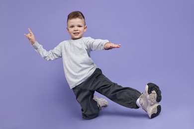 Happy little boy dancing on violet background