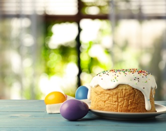 Image of Delicious Easter cake and dyed eggs on blue wooden table indoors. Space for text