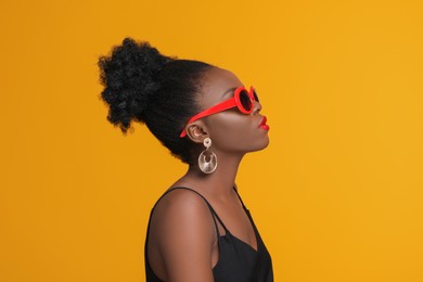 Fashionable portrait of beautiful woman with stylish sunglasses on yellow background