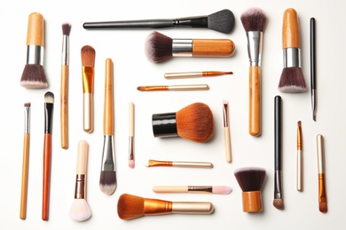 Flat lay composition with makeup brushes of professional artist on white background