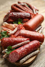 Photo of Different types of sausages served on wooden table, closeup